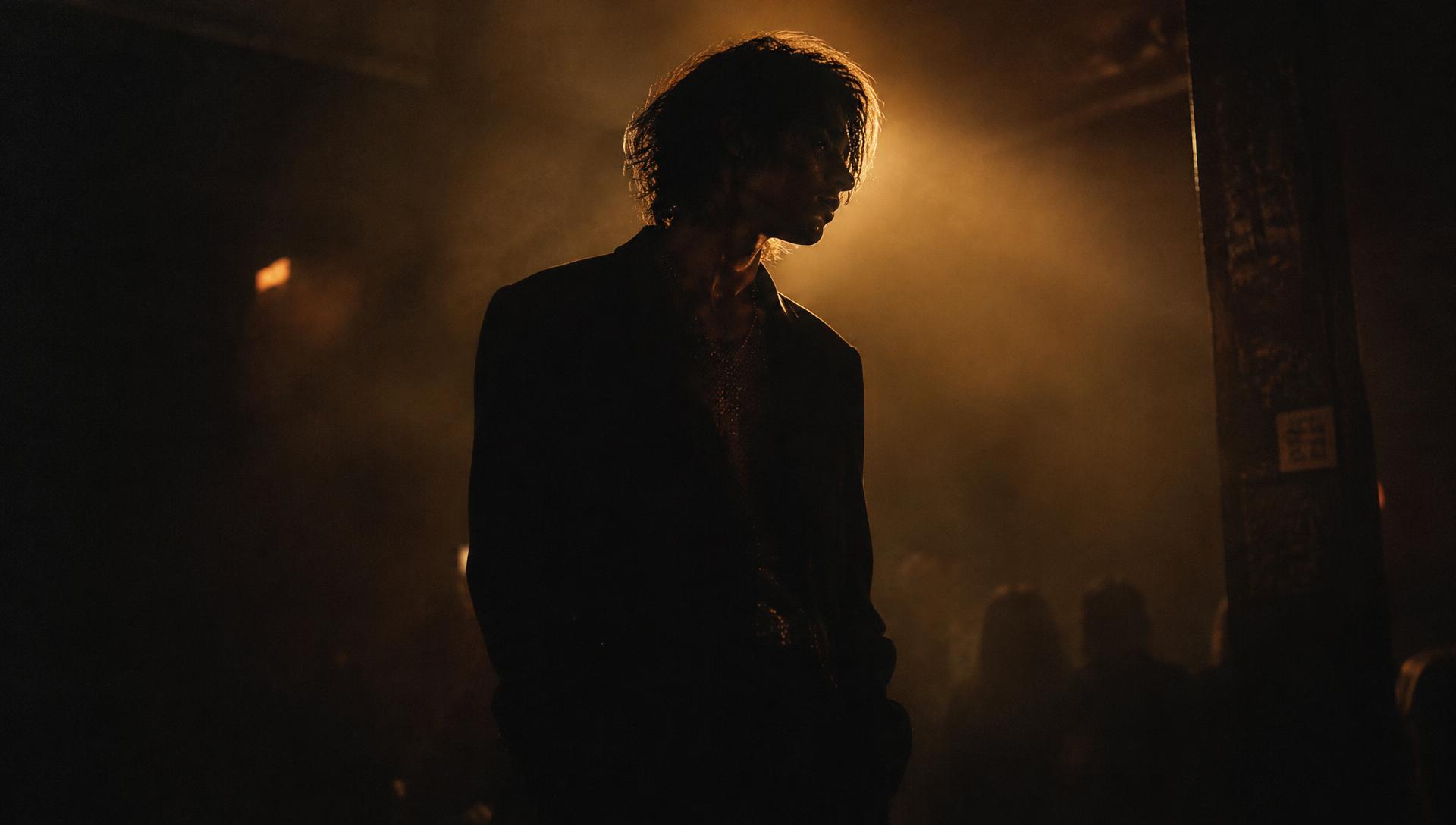 Silhouetted artist in amber club light